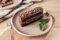 Plate with piece of delicious chocolate cake on wooden board Royalty Free Stock Photo