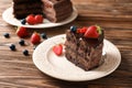 Plate with piece of tasty chocolate cake and berries on wooden table Royalty Free Stock Photo