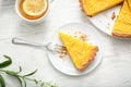 Plate with piece of tasty lemon pie and cup of tea on white wooden table Royalty Free Stock Photo