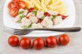 Plate with pieces chicken, pasta and row of tomatoes cherry