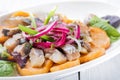 Plate of pieces of herring with fried potato,onion and salad. Close up image with selective focus Royalty Free Stock Photo