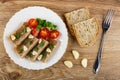 Plate with pieces of meat jelly, garlic, basil, tomato cherry, slices of bread, fork on table. Top view