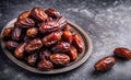 Plate of pitted dates on a dark wooden background. Top view