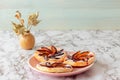 Plate with plum tarts with cinnamon and icing sugar on the table, tasty puff pastry dessert.