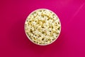 Plate with popcorn on pink paper background