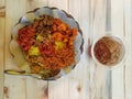 Plate of popular Indonesian Nasi Kuning or Yellow Rice with a glass of iced tea on wooden table: noodles, meat, shrimp, tofu Royalty Free Stock Photo