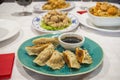 Plate with a portion of gyozas cooked on the grill, dim sum, with soy sauce, poppy seeds and sesame on a blue plate of a Chinese