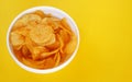Plate with potato chips on a bright yellow background Royalty Free Stock Photo