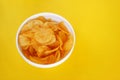 Plate with potato chips on a bright yellow background Royalty Free Stock Photo