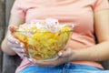 A plate of potato chips and a centimeter tape in the girl`s hands. Junk food. The concept of struggle against excess weight.