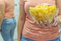 A plate of potato chips and a centimeter tape in the girl`s hands. Junk food. The concept of struggle against excess weight.