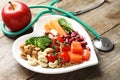 Plate with products for heart-healthy diet, apple and stethoscope on background