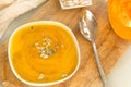 Plate of pumpkin vegetable soup with seeds on the Board, a spoon, a piece of fresh raw pumpkin Royalty Free Stock Photo