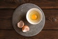 Plate with raw broken egg, shell on concrete slab