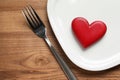 Plate with red heart, fork and space for text on wooden table, flat lay.