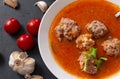 1 plate of red tomato soup with meatballs, garlic and cilantro on a black background close up, fresh cherry