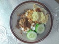 a plate of rice with side dishes of rendang, chips melinjo and cucumber slices. simple but really delicious