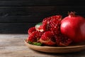 Plate with ripe pomegranates on wooden table against dark background Royalty Free Stock Photo