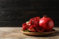 Plate with ripe pomegranates on wooden table against dark background Royalty Free Stock Photo