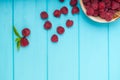 Plate of ripe raspberries with spilled fruit