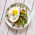 A plate of roasted salmon, sauteed asparagus and a fried egg on top.