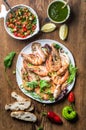 Plate of roasted tiger prawns and octopus with fresh leek, green salad, peppers, lemon, bread, pesto sauce over wooden Royalty Free Stock Photo