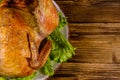 Plate with roasted whole chicken and lettuce leaves on a wooden table. Top view