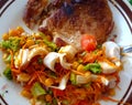 A plate of salad with vegetables heart of palm, tomato, onion, carrot, green corn, broccoli, lettuce and pork chop, grilled pork Royalty Free Stock Photo