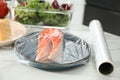 Plate of salmon with plastic food wrap on white marble table in kitchen, closeup Royalty Free Stock Photo