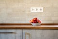 A plate with Saturn peaches on a wooden table in the kitchen. Peaches on a kitchen table against a brick wall with power sockets Royalty Free Stock Photo