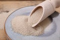 Plate and scoop with active dry yeast on wooden table, closeup Royalty Free Stock Photo