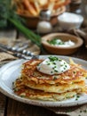 A plate of scrumptious potato pancakes topped with a dollop of sour cream and sprinkled with chives, with a cozy rustic