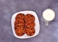 A plate with several oatmeal chocolate chip cookies and a glass of hot milk on a gray background Royalty Free Stock Photo