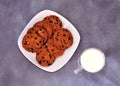 A plate with several oatmeal chocolate chip cookies and a glass of hot milk on a gray background Royalty Free Stock Photo