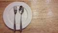 Plate and silverwear including spoon and fork on wood background