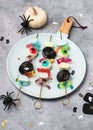 Plate with skewers of colorful jelly, eyeballs, candy and marshmallows. Sweet Halloween kids party food concept.