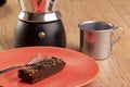 Plate with a slice of brownie, a coffee maker and a cup of coffee