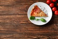 Plate with slice of tasty pepperoni pizza and tomatoes on wooden table Royalty Free Stock Photo