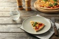 Plate with slice of tasty pizza on wooden table Royalty Free Stock Photo