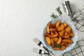 Plate of sliced baked potato wedges, salt, forks on white background, top view. Space for text