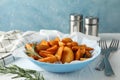 Plate of sliced baked potato wedges, salt, forks on white table, against blue background, space for text. Closeup Royalty Free Stock Photo