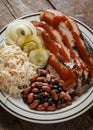 A plate of sliced brisket with baked beans, cole slaw and dill