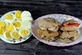 A plate of slices of boiled eggs and Sandwiches of Feta white cheese with slices of tomatoes and traditional plain tahini halva or