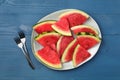 Plate with slices of juicy watermelon on blue wooden table, top view Royalty Free Stock Photo