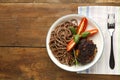 Plate soba with chicken tomatoes and spinach on a napkin next to a fork