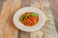 Plate of spaghetti with lots of bolognese sauce and minced beef topped with basil leaves on white plate