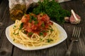 A plate of spaghetti with meatballs in tomato sauce and some ingredients for cooking on the backdrop Royalty Free Stock Photo