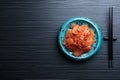 Plate of spicy cabbage kimchi and chopsticks on black wooden table, flat lay. Space for text Royalty Free Stock Photo