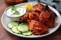 plate of spicy tandoori chicken with side of cool cucumber raita