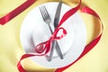 Plate with spoon, knife and fork tied with red ribbon Royalty Free Stock Photo